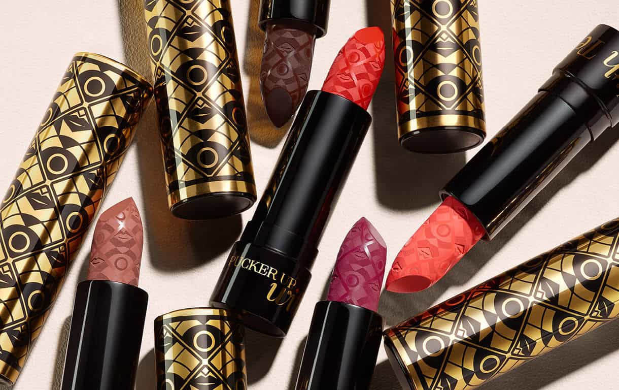Elegant lipstick tubes with intricate gold and black geometric designs.