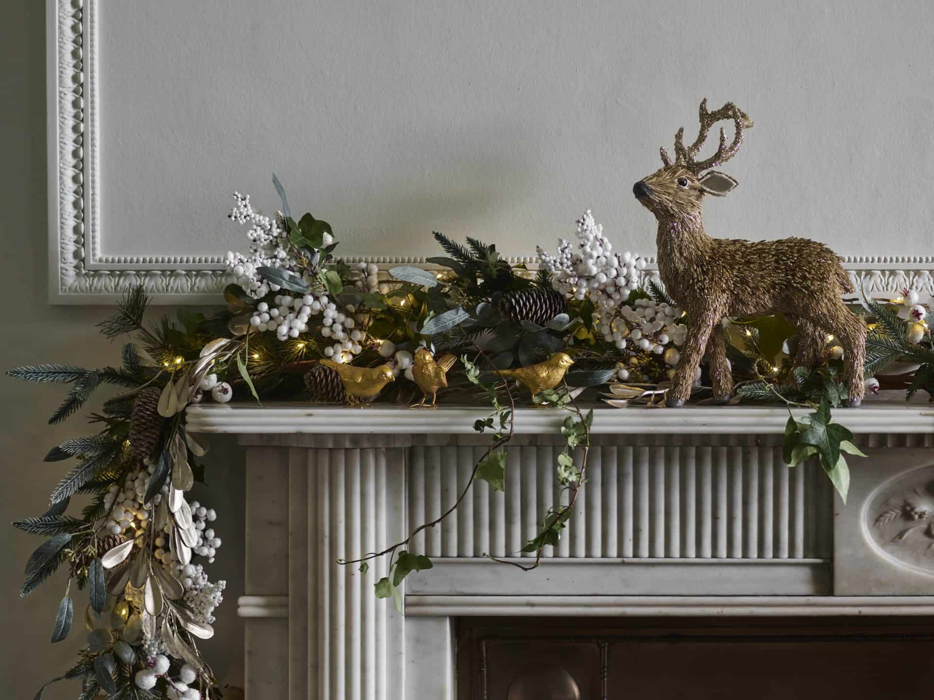 Elegant Christmas mantel with greenery, ornaments, and reindeer figure at Victoria Leeds.