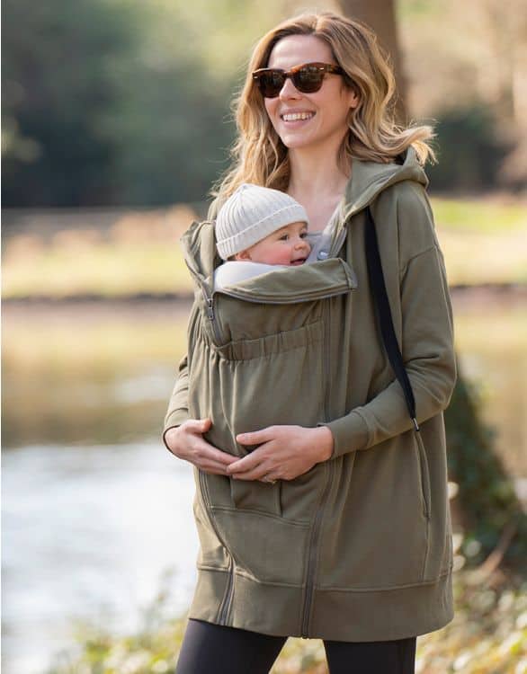 Mother carrying baby in a comfortable carrier outdoors.