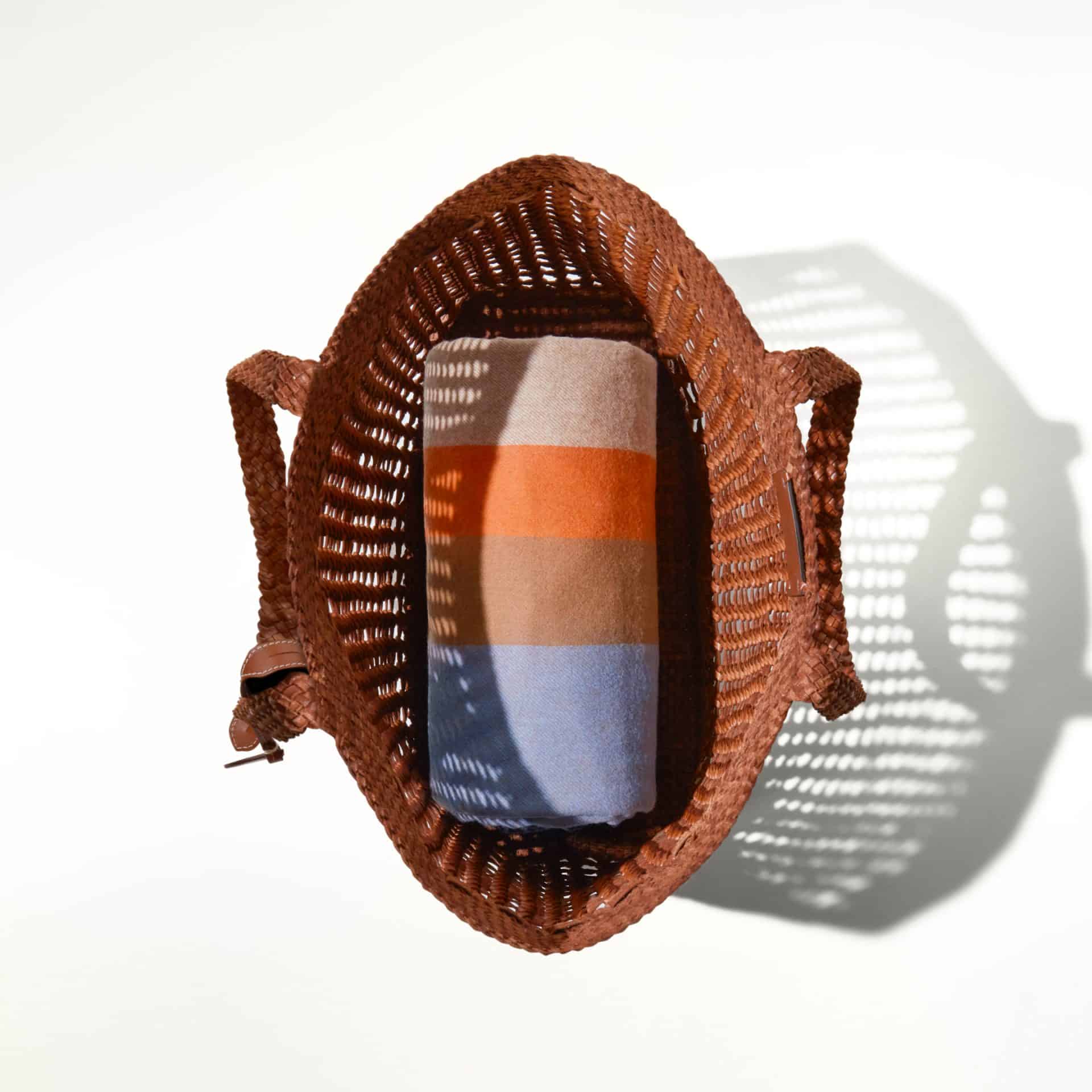 Wicker picnic basket with colourful striped blanket inside, perfect for summer outings.