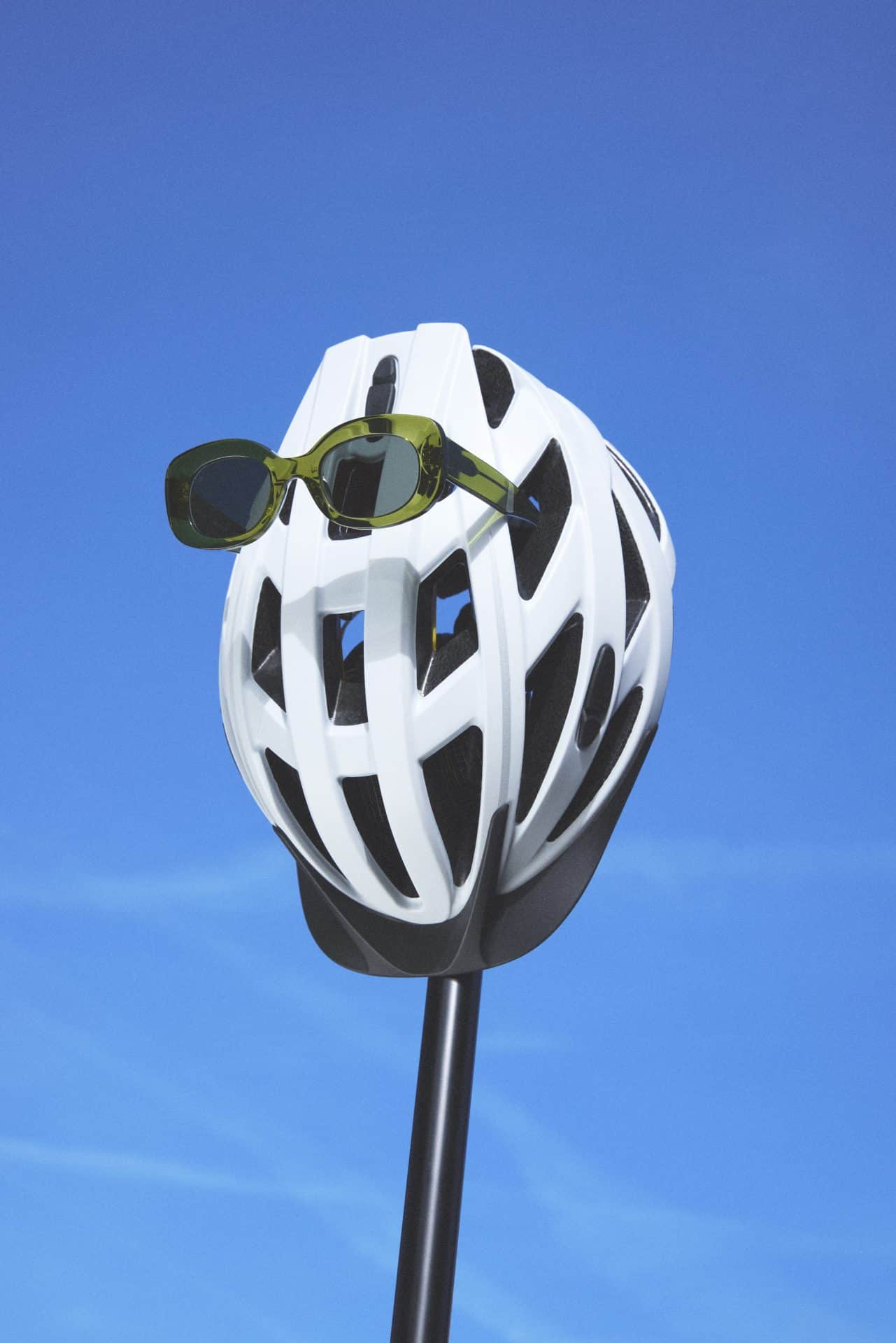 White helmet with green sunglasses against a blue sky.