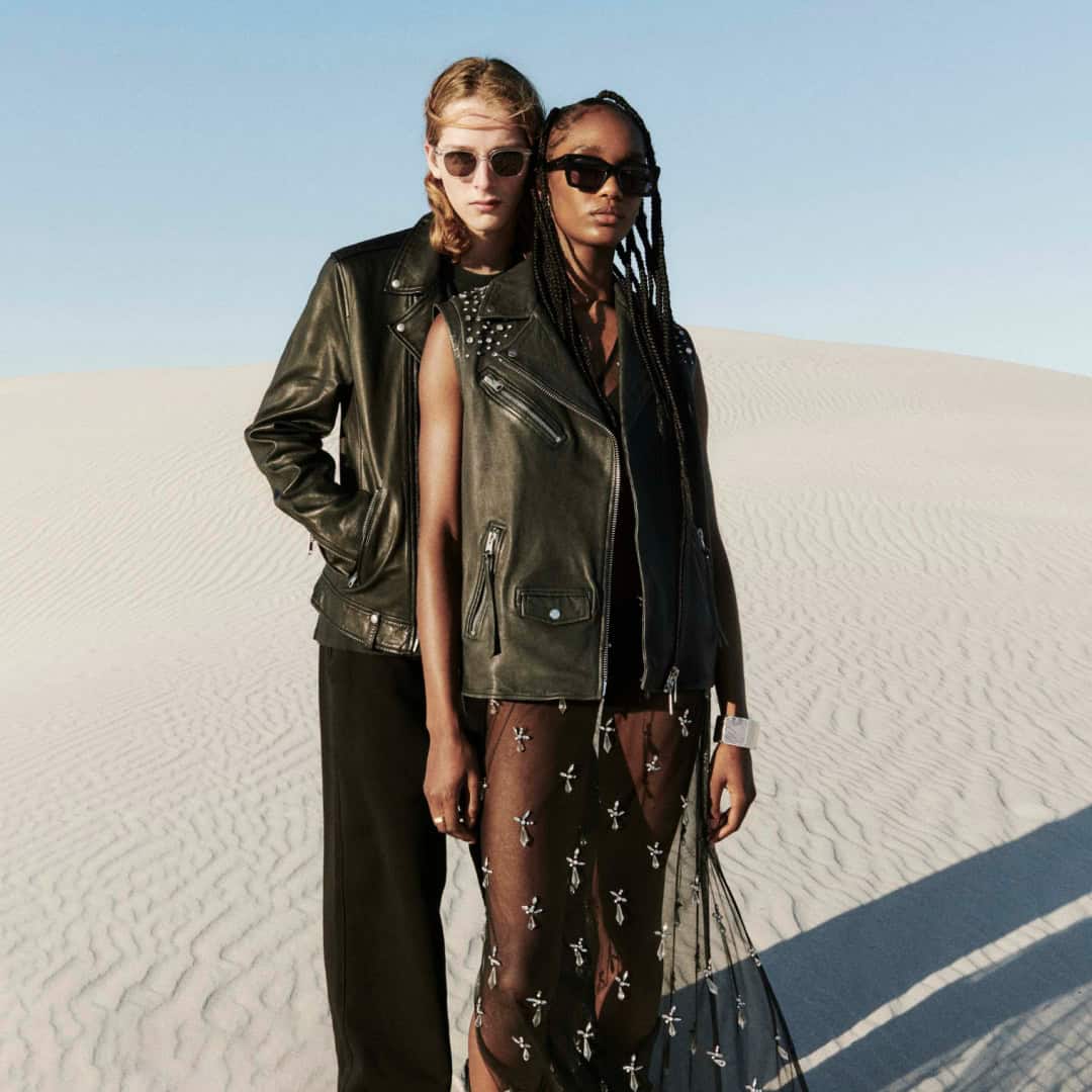 Fashion models wearing AllSaints Summer 24 collection in desert setting.