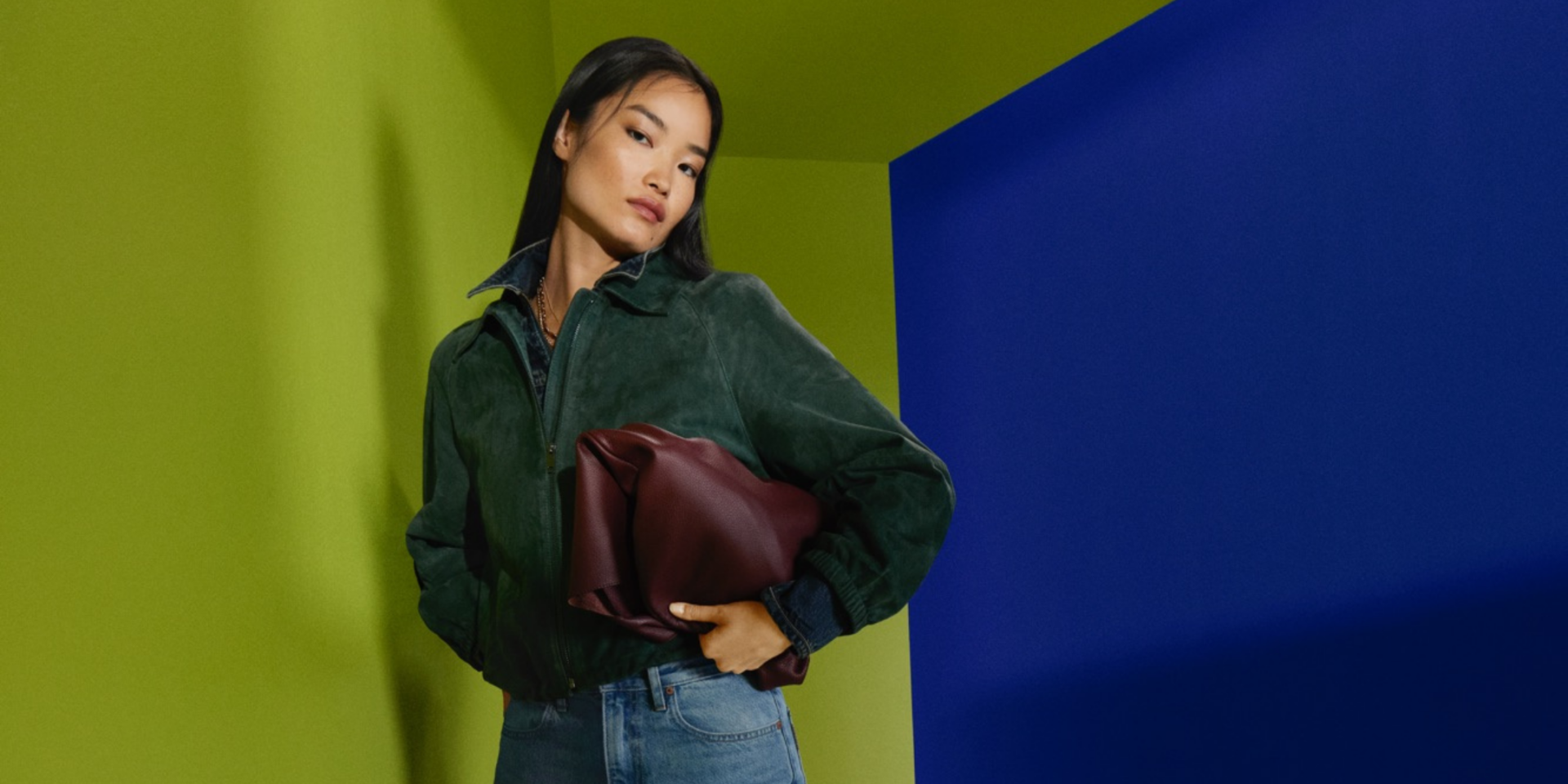 Stylish woman in green jacket holding a brown bag at Victoria Leeds.