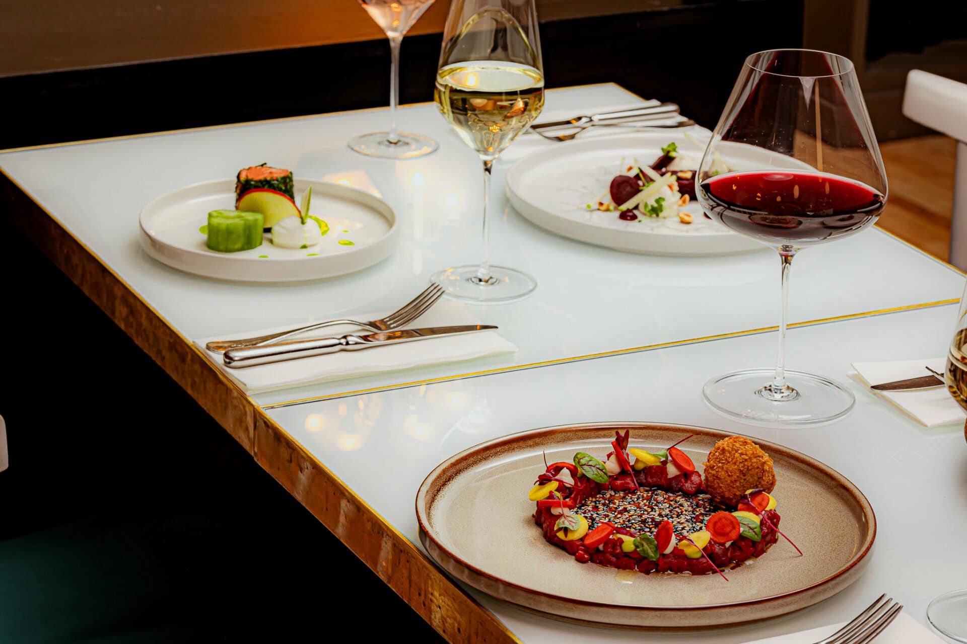 Elegant fine dining table with gourmet dishes and wine glasses in a sophisticated setting.