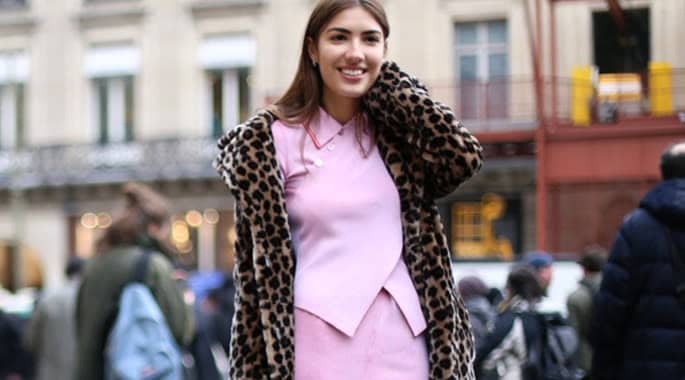 Elegant woman wearing a leopard print faux fur coat in an urban setting.