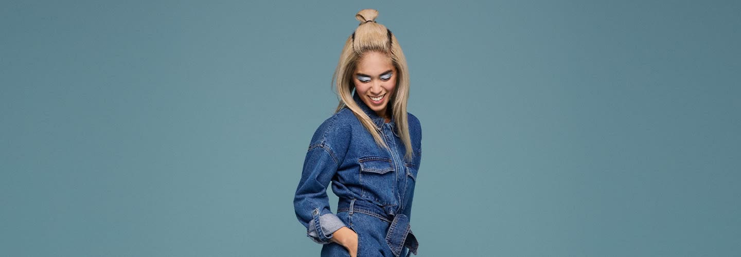 Stylish young woman in denim jacket smiling confidently.