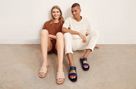 Two young adults sitting on the floor, smiling, in casual outfits at Victoria Leeds.