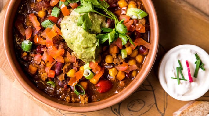 Colourful vegetable stew with avocado and sour cream, vibrant and healthy meal option.