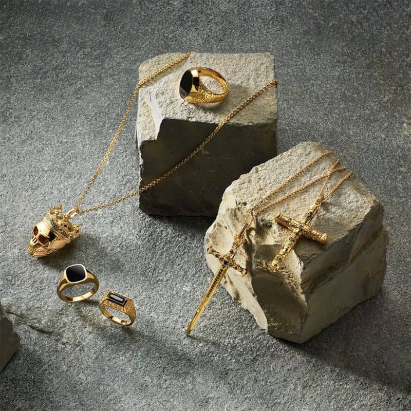 Gold jewelry including rings, necklaces, and bracelets displayed on stone blocks.