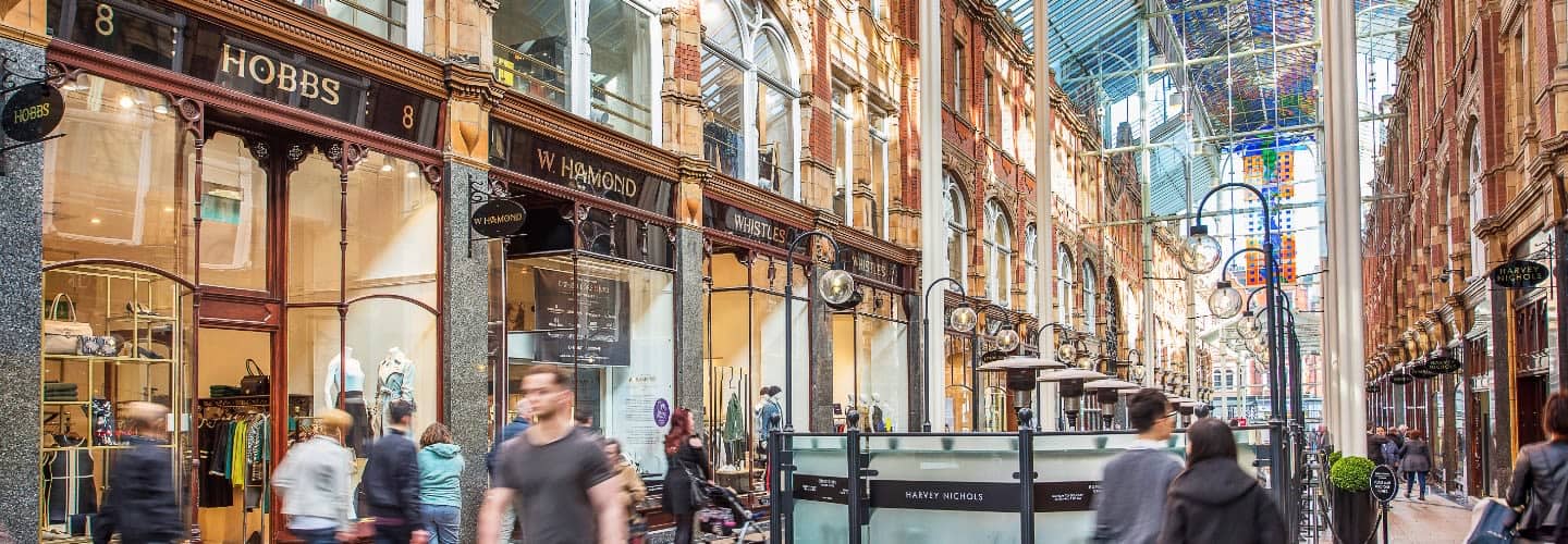Victoria Leeds shopping arcade with historic architecture and bustling shoppers.