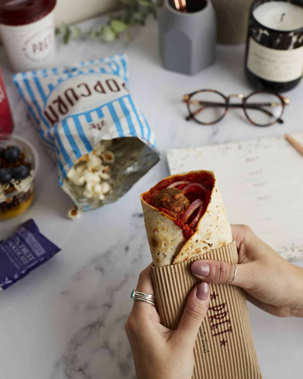 Hand holding a gourmet wrap with vegetables and meat at Victoria Leeds.