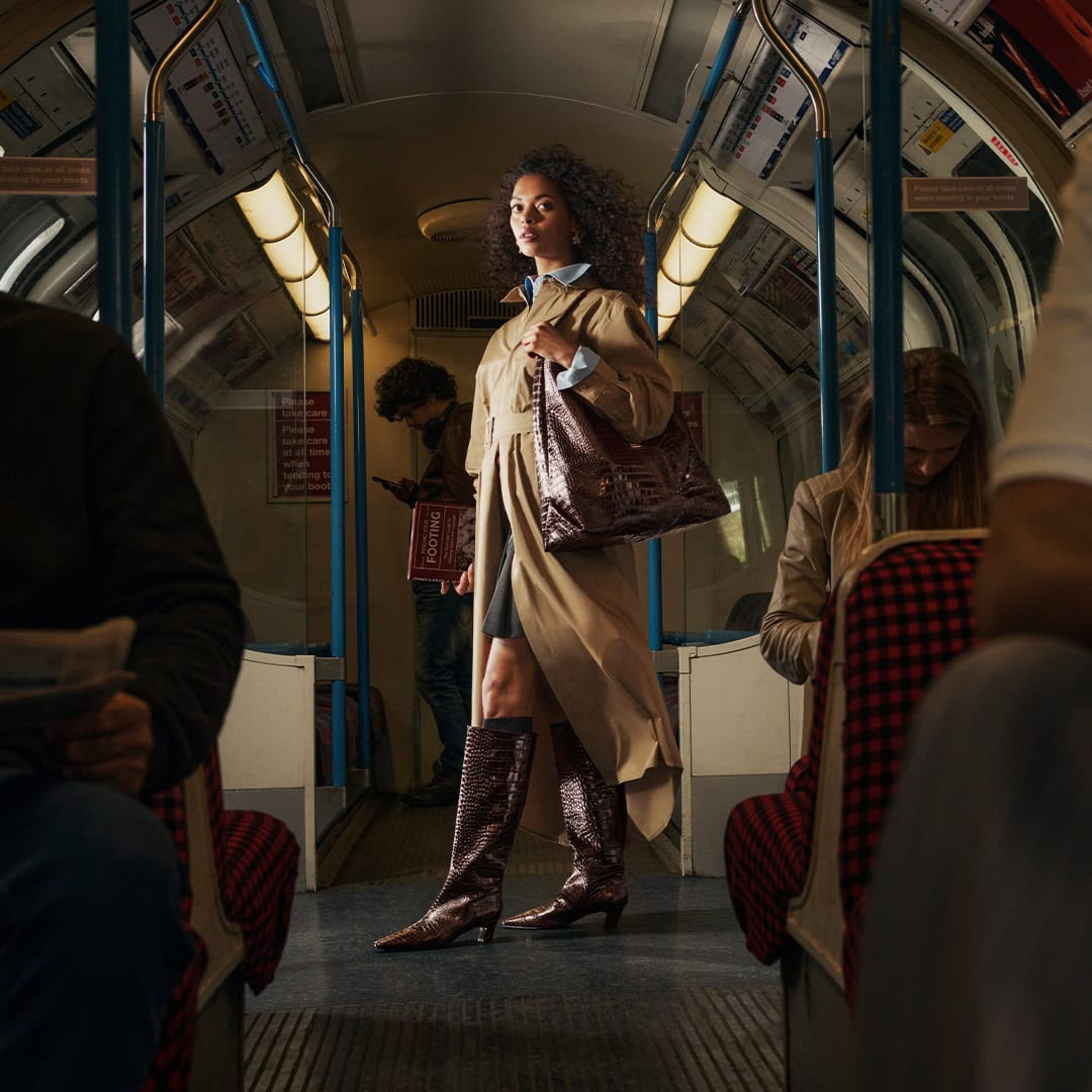 Woman in fashionable coat and boots standing on bus in Leeds.