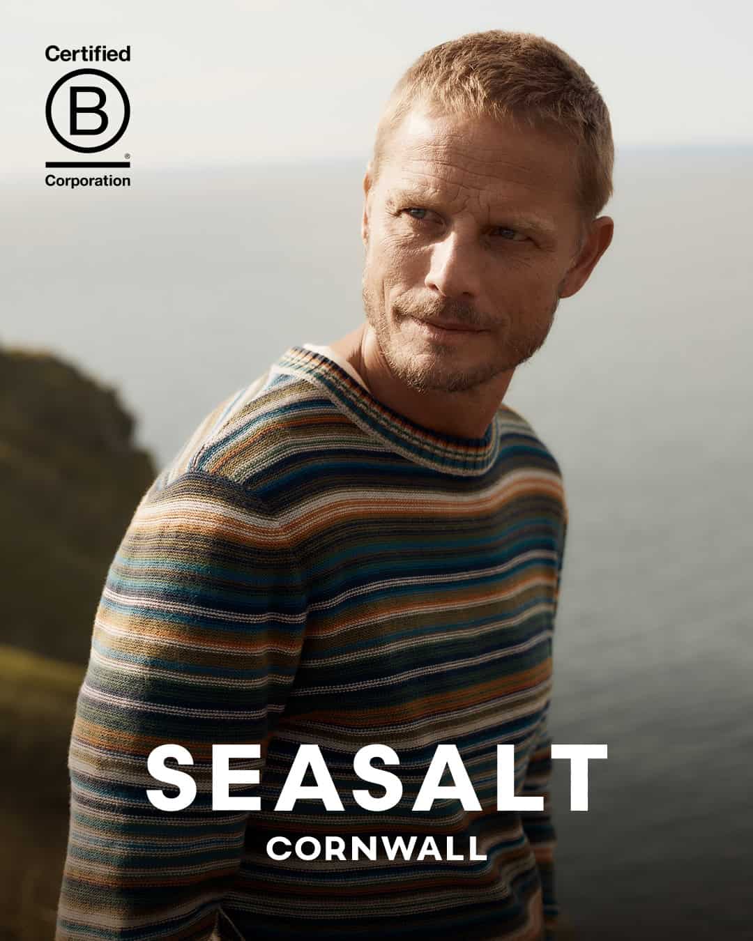 Man wearing Seasalt striped sweater outdoors near coast.