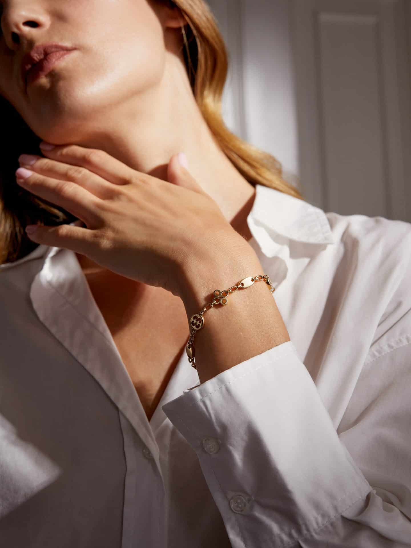 Elegant gold bracelet with charms on woman's wrist.
