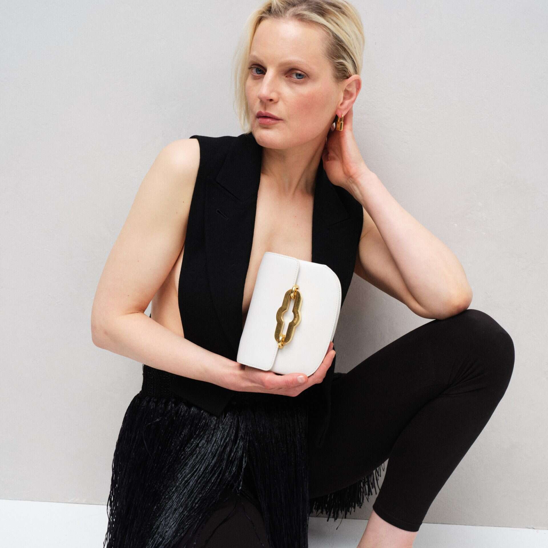 Stylish white clutch bag with gold clasp, perfect for evening events.