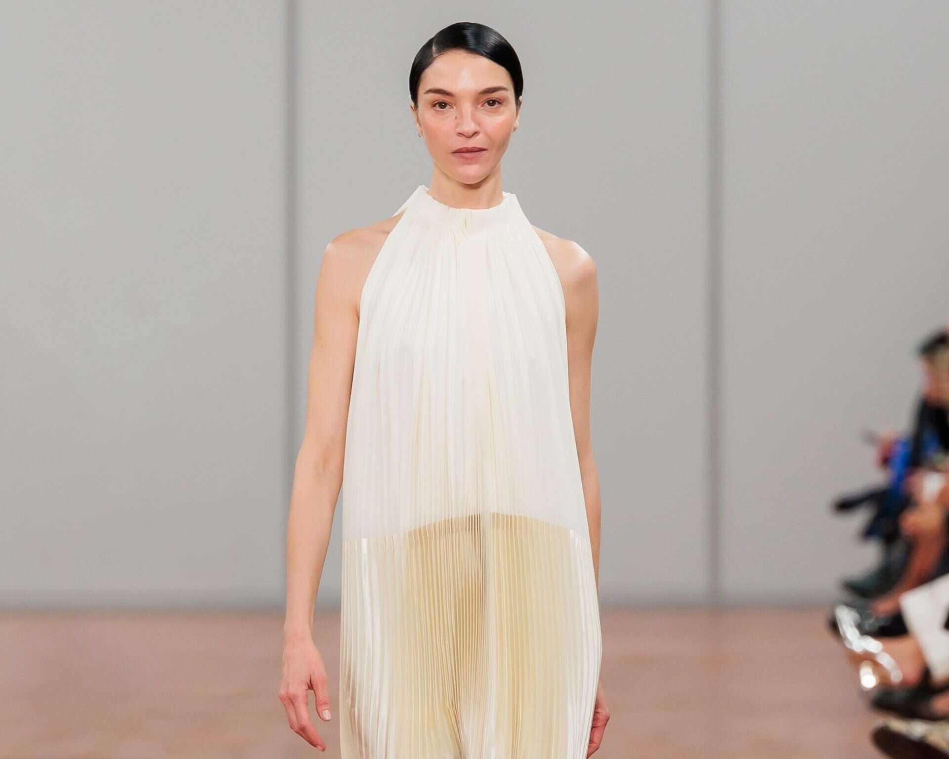 Elegant model walking the runway in a flowing cream dress at Victoria Leeds COS SS24 show.