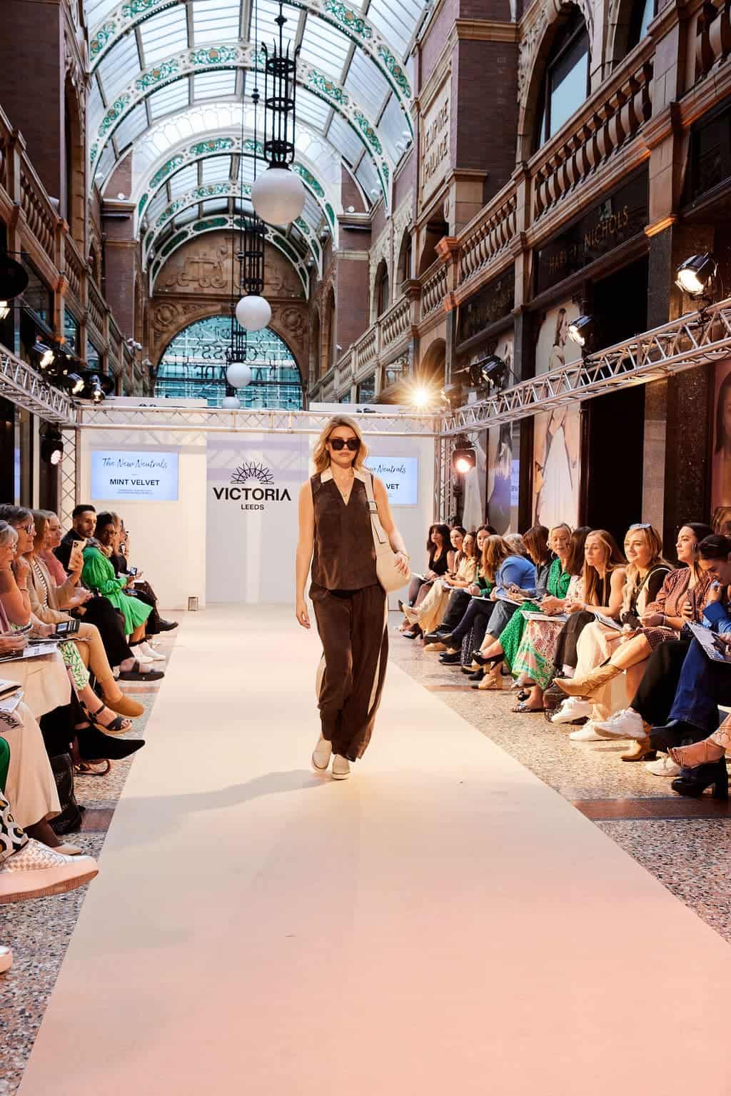 Elegant model walking runway at Victoria Leeds fashion event.