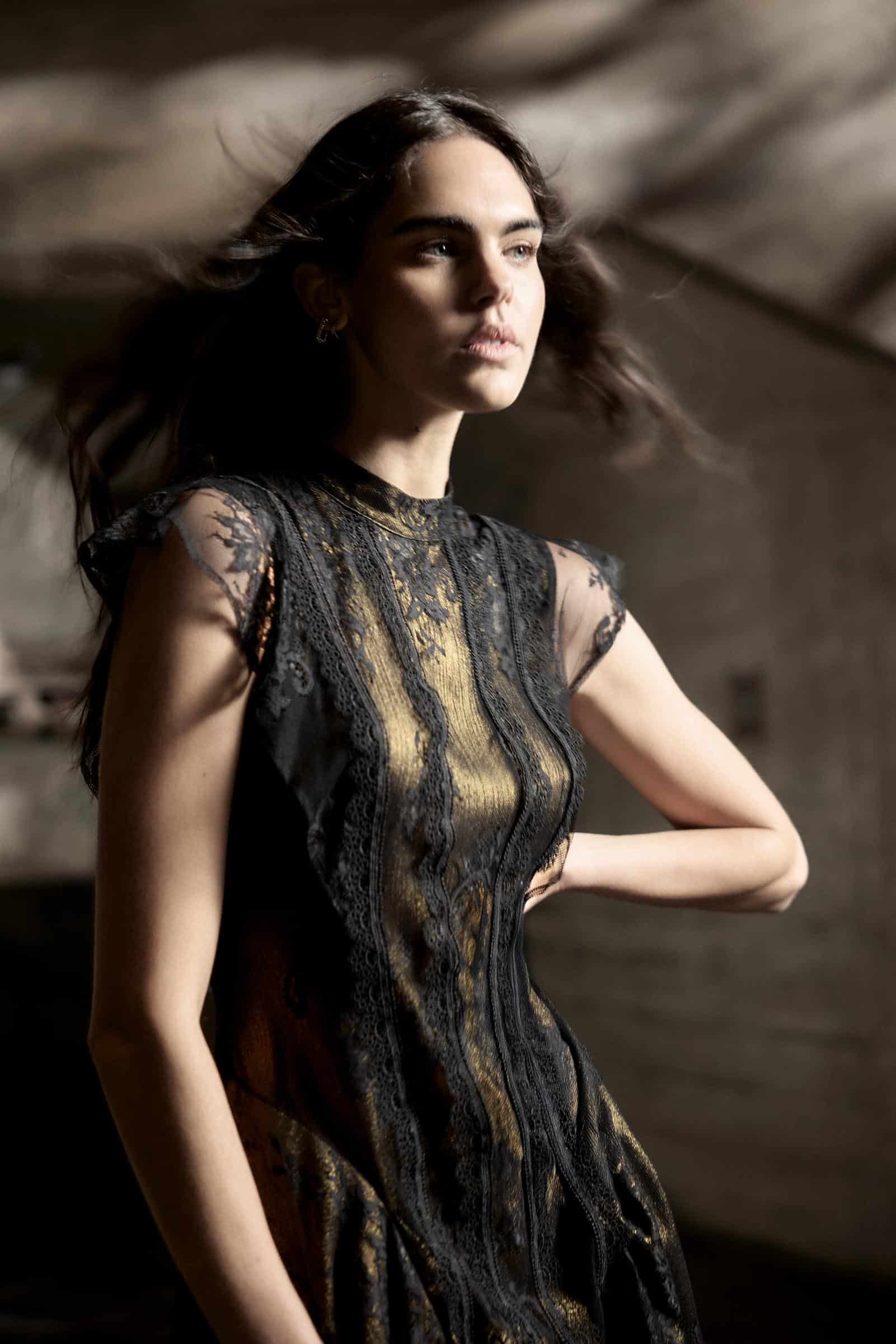 Elegant woman in a black and gold lace dress, showcasing stylish evening wear at Victoria Leeds.