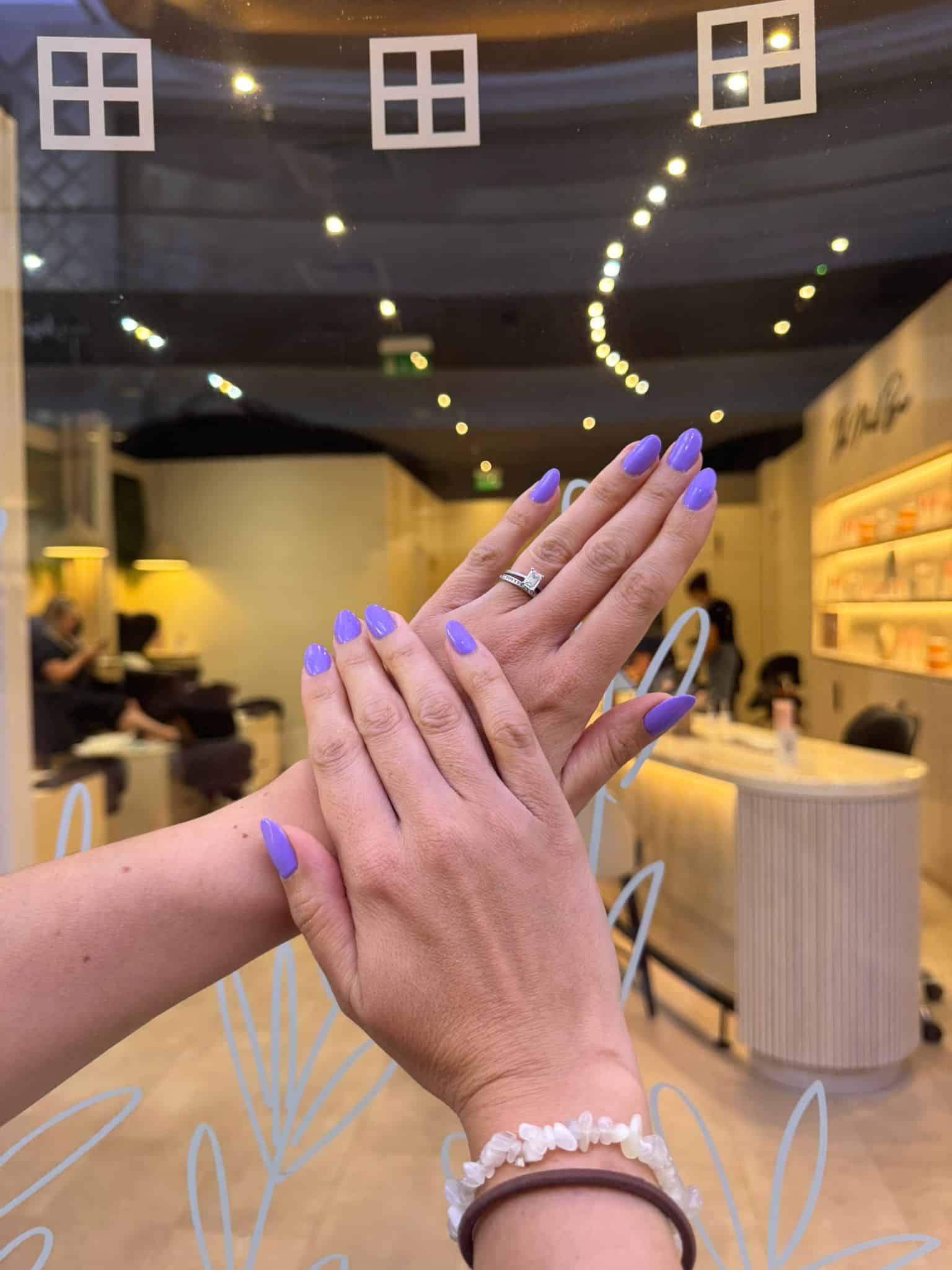 Hands with purple nails and jewelry at Victoria Leeds wellness event.