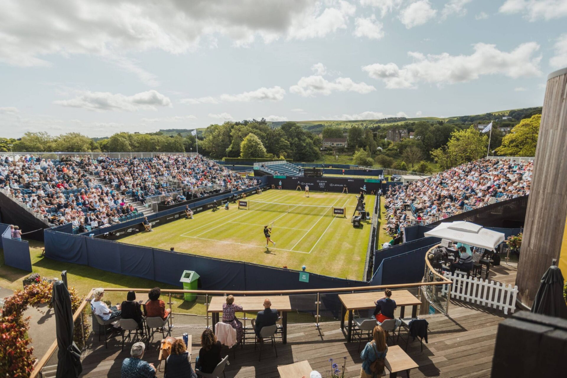 Tennis match at Victoria Leeds with spectators enjoying the outdoor event.