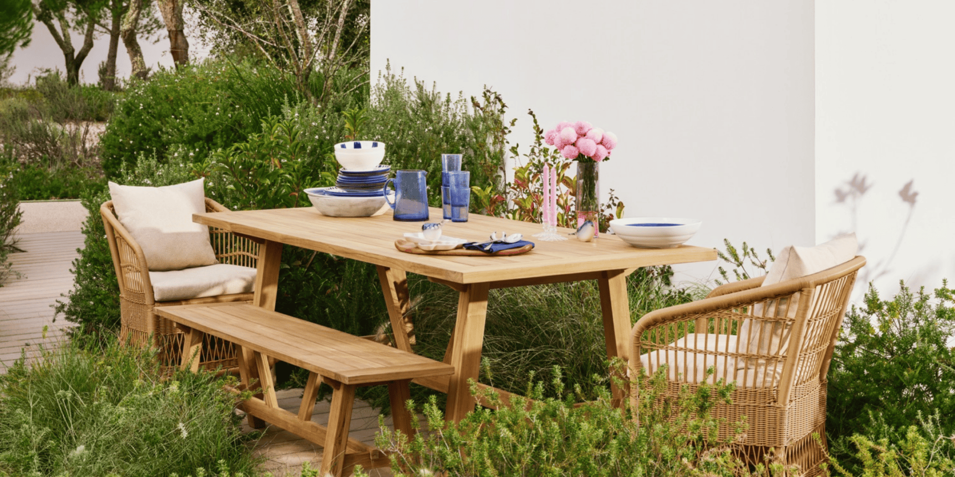A lush outdoor dining area with wooden furniture and colourful tableware for summer gatherings.