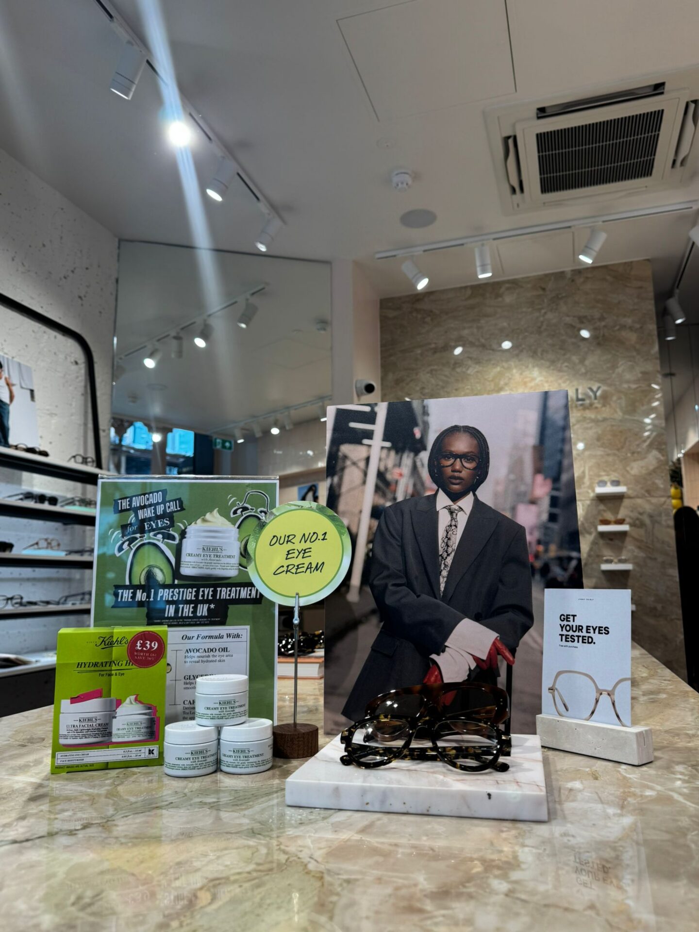 Victoria Leeds retail display with skincare and eyewear products and a portrait of a man in a suit.