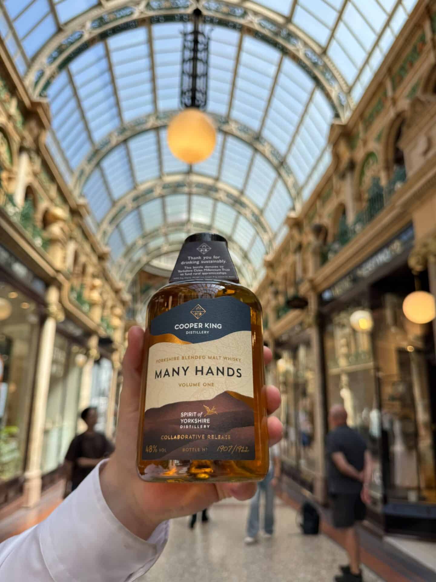 Cooper King Many Hands whisky bottle held in Victoria Leeds shopping arcade.