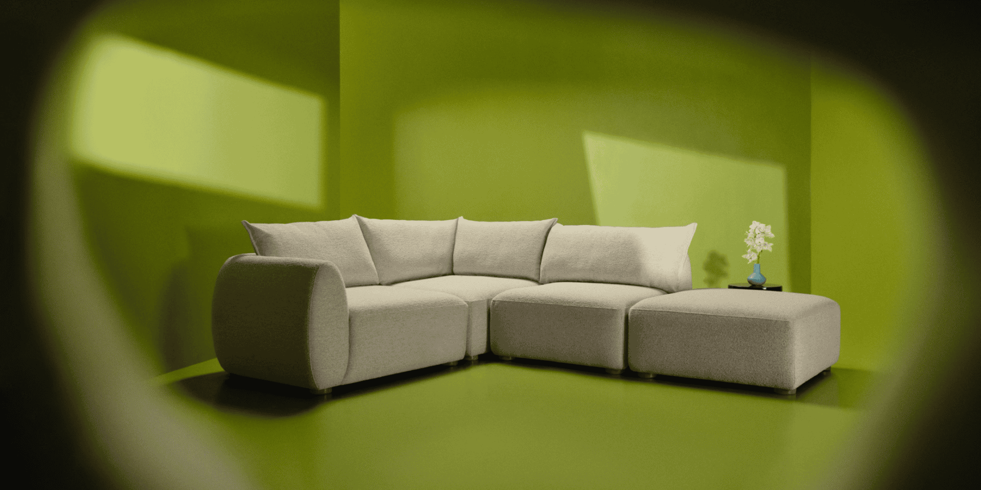 Modern beige sectional sofa in a vibrant green room with a small side table.